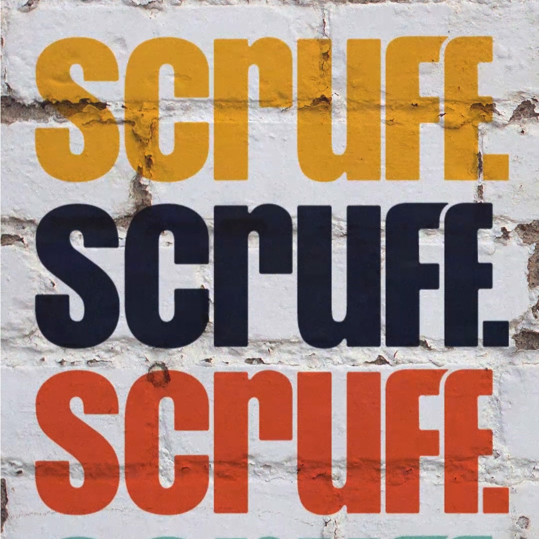Scruff logo painted vertically on a white brick wall in yellow, navy, and orange